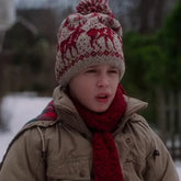 Person wearing a patterned knit hat and red scarf in a snowy setting