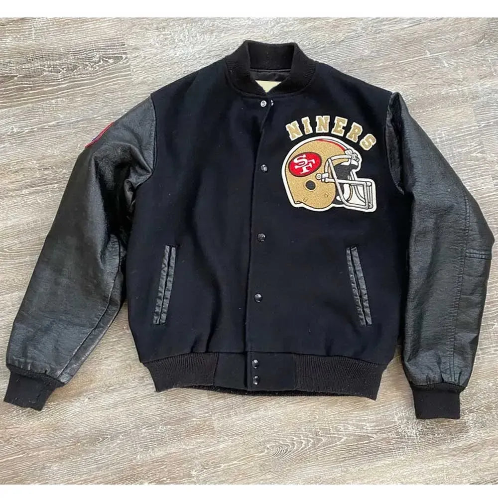 Black varsity jacket with '49ers' logo on a wooden surface