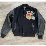 Black varsity jacket with '49ers' logo on a wooden surface