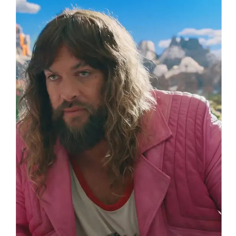 Person with long hair and beard wearing a pink jacket in a scenic outdoor setting