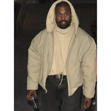 Person wearing a beige hoodie and dark pants in a dimly lit setting