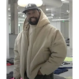 Man wearing a beige hoodie and black cap with 'FA' logo indoors.